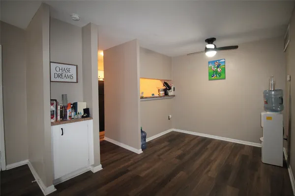 a view of a hallway with wooden floor and a bathroom