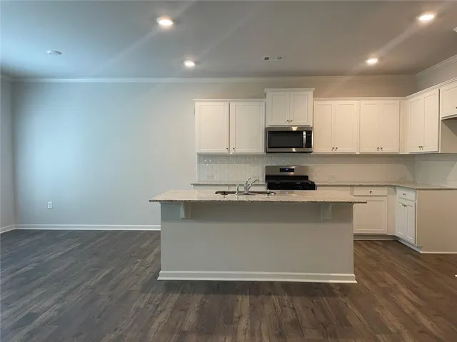 a kitchen with granite countertop a stove a sink and a microwave