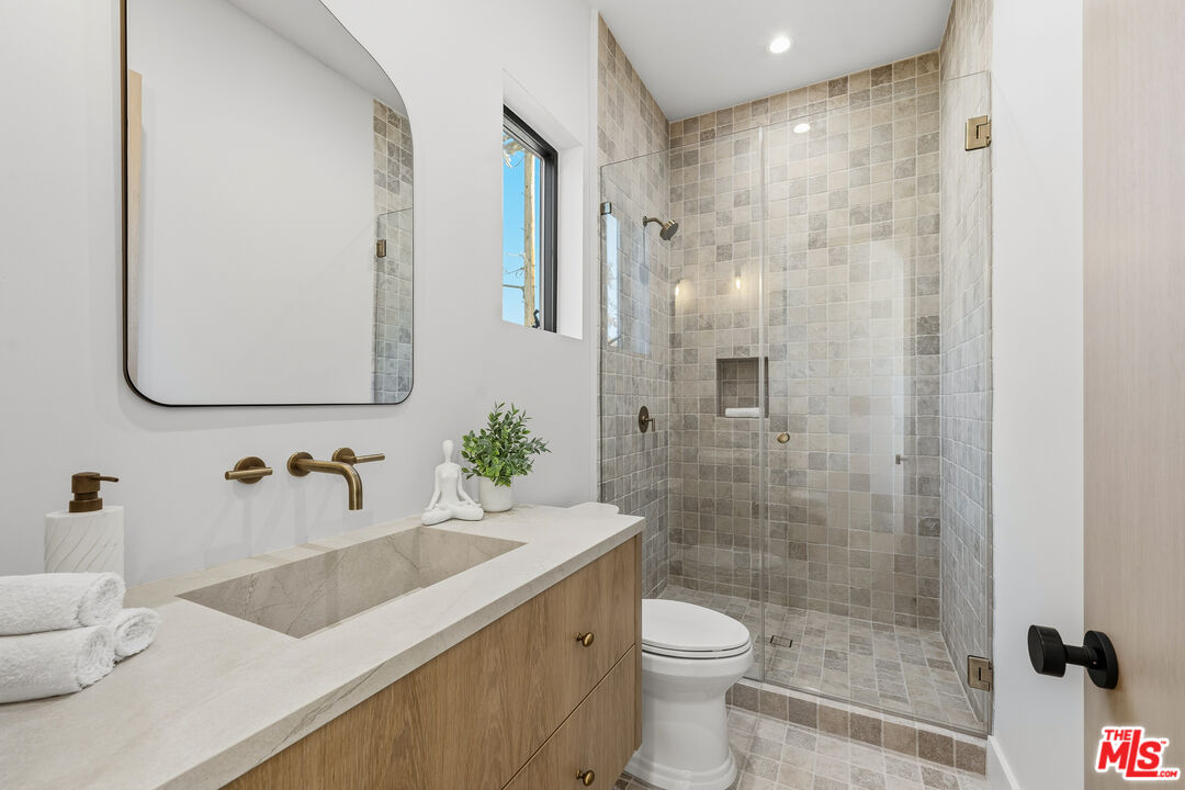 16643 Addison Street Encino, CA 91436 - Photo 25 of 31 a bathroom with a granite countertop sink a toilet and shower