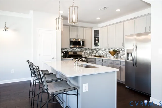 a kitchen with stainless steel appliances granite countertop a sink a stove a refrigerator a dining table and chairs