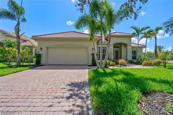 a front view of a house with a garden and palm trees