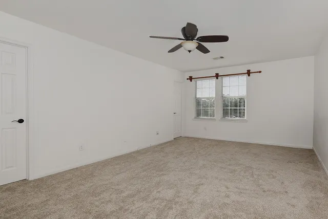 an empty room with windows and fan view