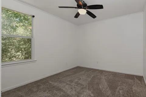 an empty room with a window and a fan