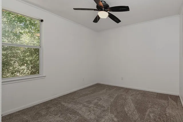 an empty room with a window and a fan