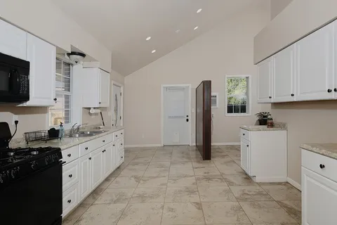 a kitchen with granite countertop a refrigerator stove top oven and sink