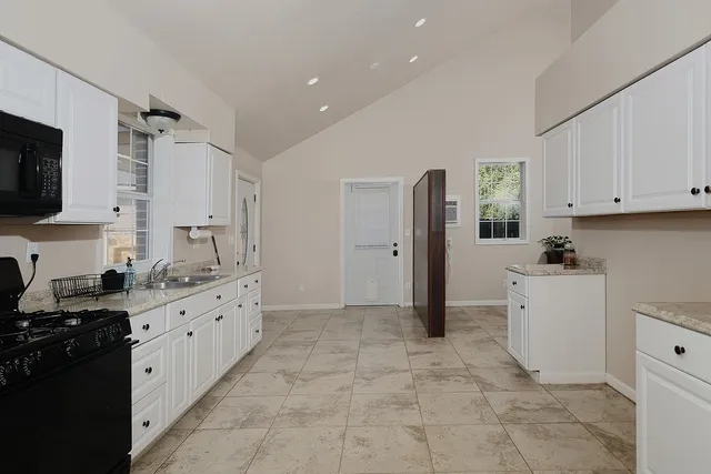 a kitchen with granite countertop a refrigerator stove top oven and sink
