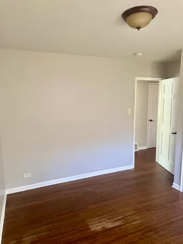 a view of an empty room with wooden floor and a large window