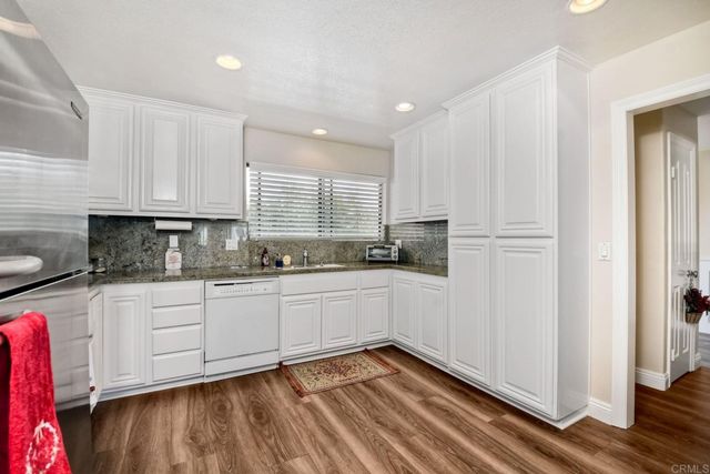 a kitchen with stainless steel appliances granite countertop a refrigerator a stove and white cabinets