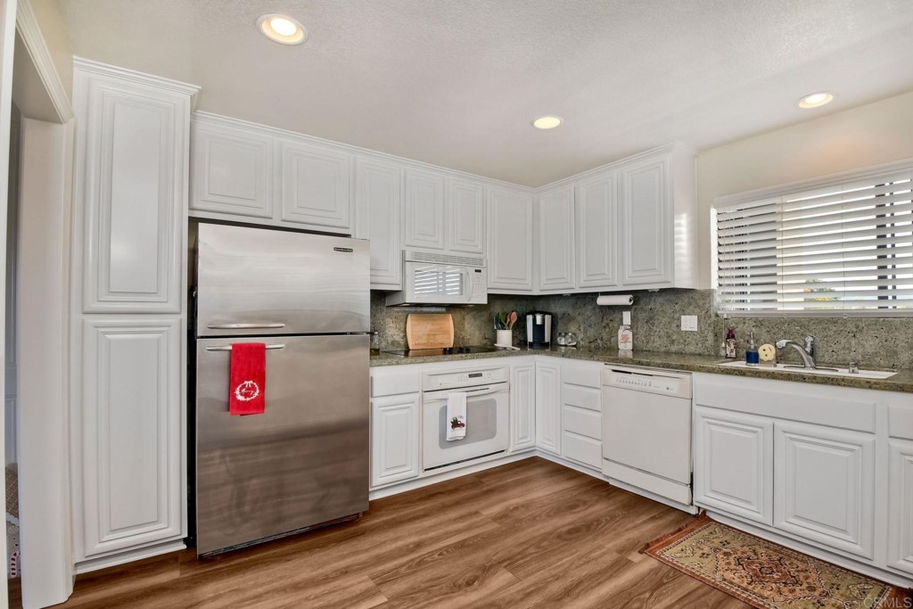 4705 Marina Drive, Unit 5 Carlsbad, CA 92008 - Photo 13 of 30 a kitchen with granite countertop white cabinets and white appliances