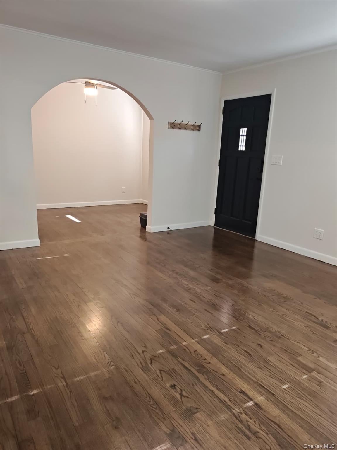 Entryway with arched walkways, crown molding, and dark wood finished floors