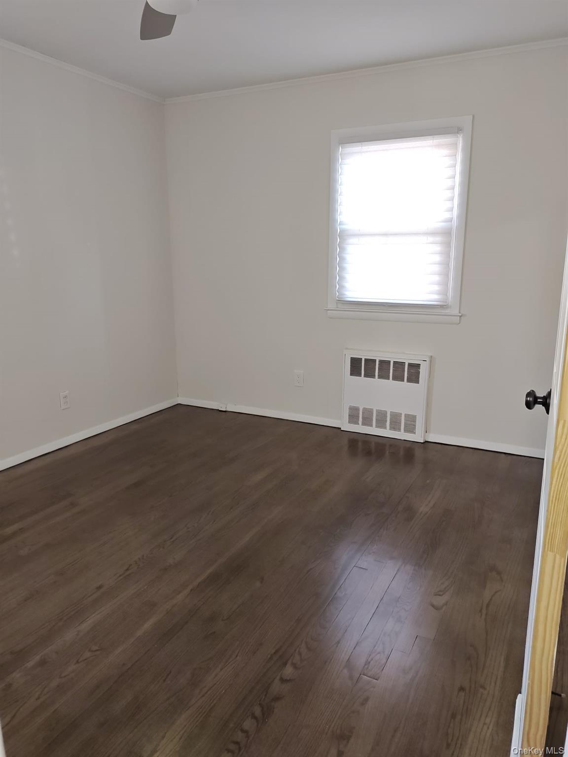 2354 North Wading River Road Wading River, NY 11792 - Photo 11 of 20 Spare room with ornamental molding, dark wood-type flooring, and radiator
