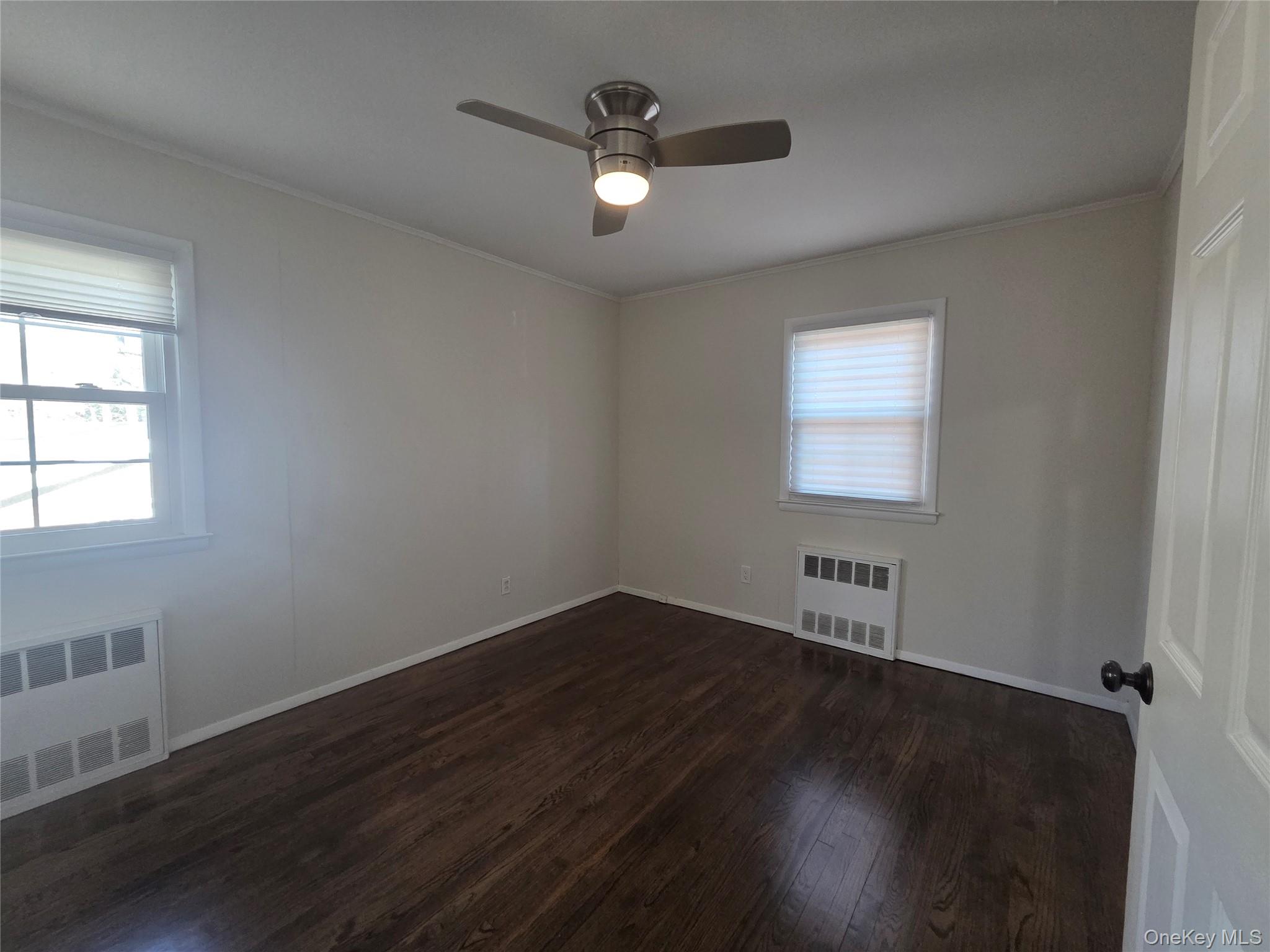 2354 North Wading River Road Wading River, NY 11792 - Photo 11 of 28 Unfurnished room featuring radiator, dark wood-type flooring, ornamental molding, and plenty of natural light
