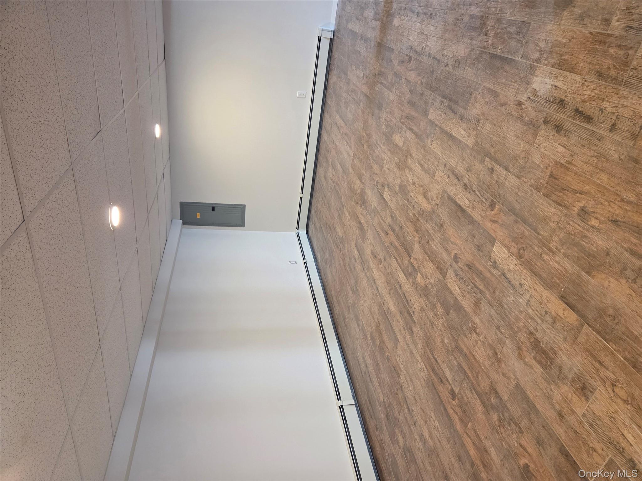 2354 North Wading River Road Wading River, NY 11792 - Photo 21 of 28 Finished below grade area featuring a baseboard radiator, a drop ceiling, wood finished floors, electric panel, and recessed lighting