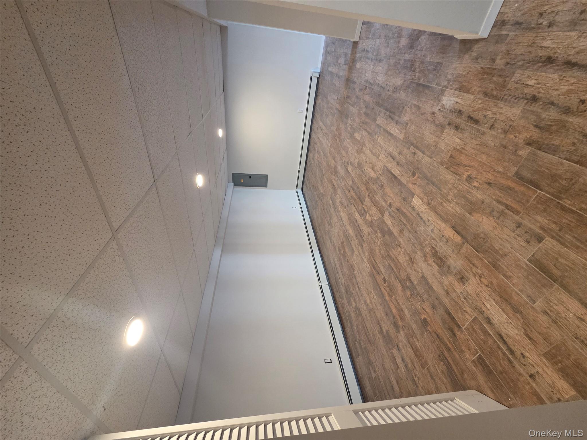 2354 North Wading River Road Wading River, NY 11792 - Photo 22 of 28 Finished below grade area featuring dark wood finished floors, a baseboard radiator, recessed lighting, a drop ceiling, and electric panel