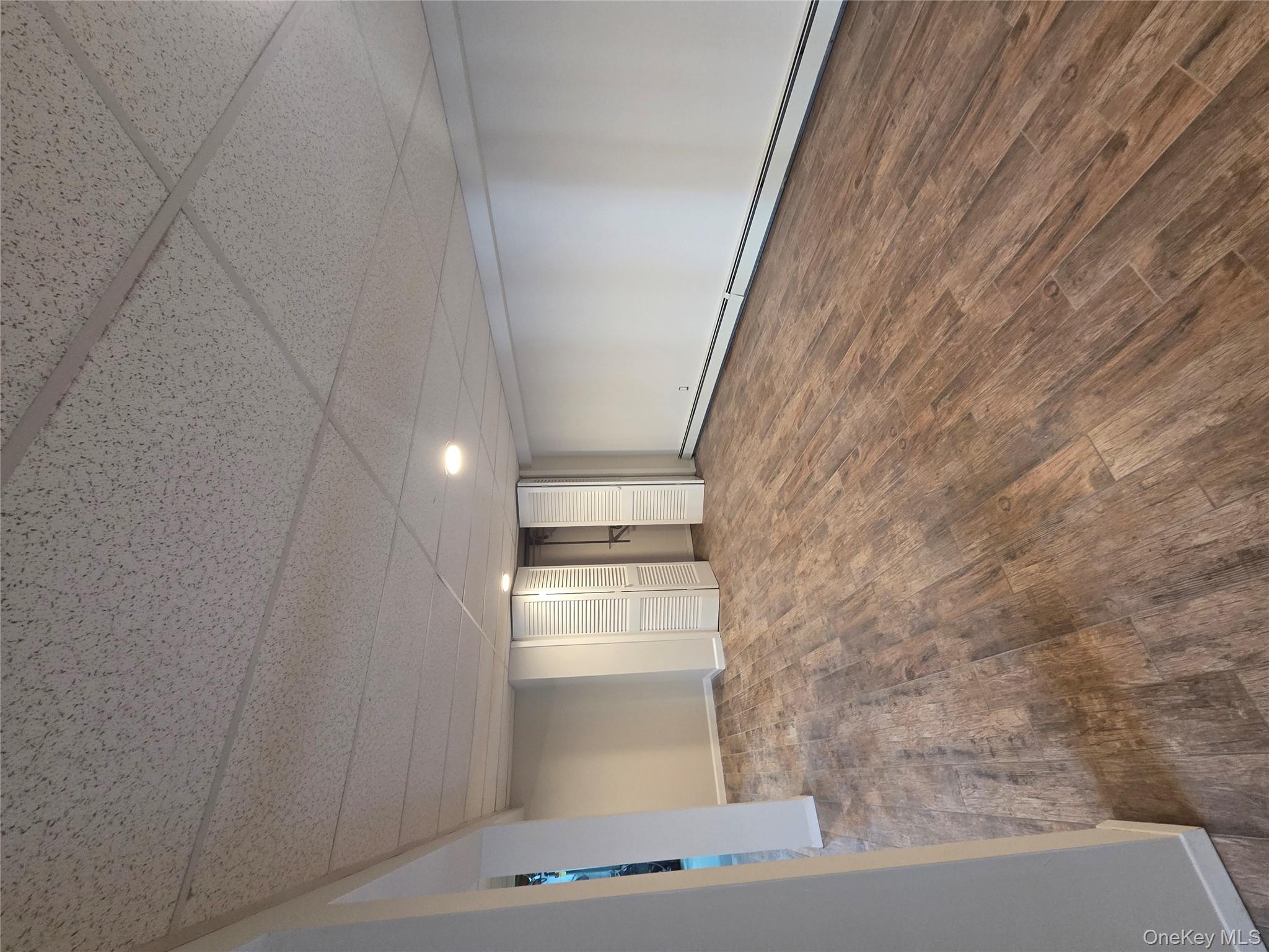 2354 North Wading River Road Wading River, NY 11792 - Photo 23 of 28 Finished below grade area with baseboard heating, dark wood-style flooring, a drop ceiling, and recessed lighting