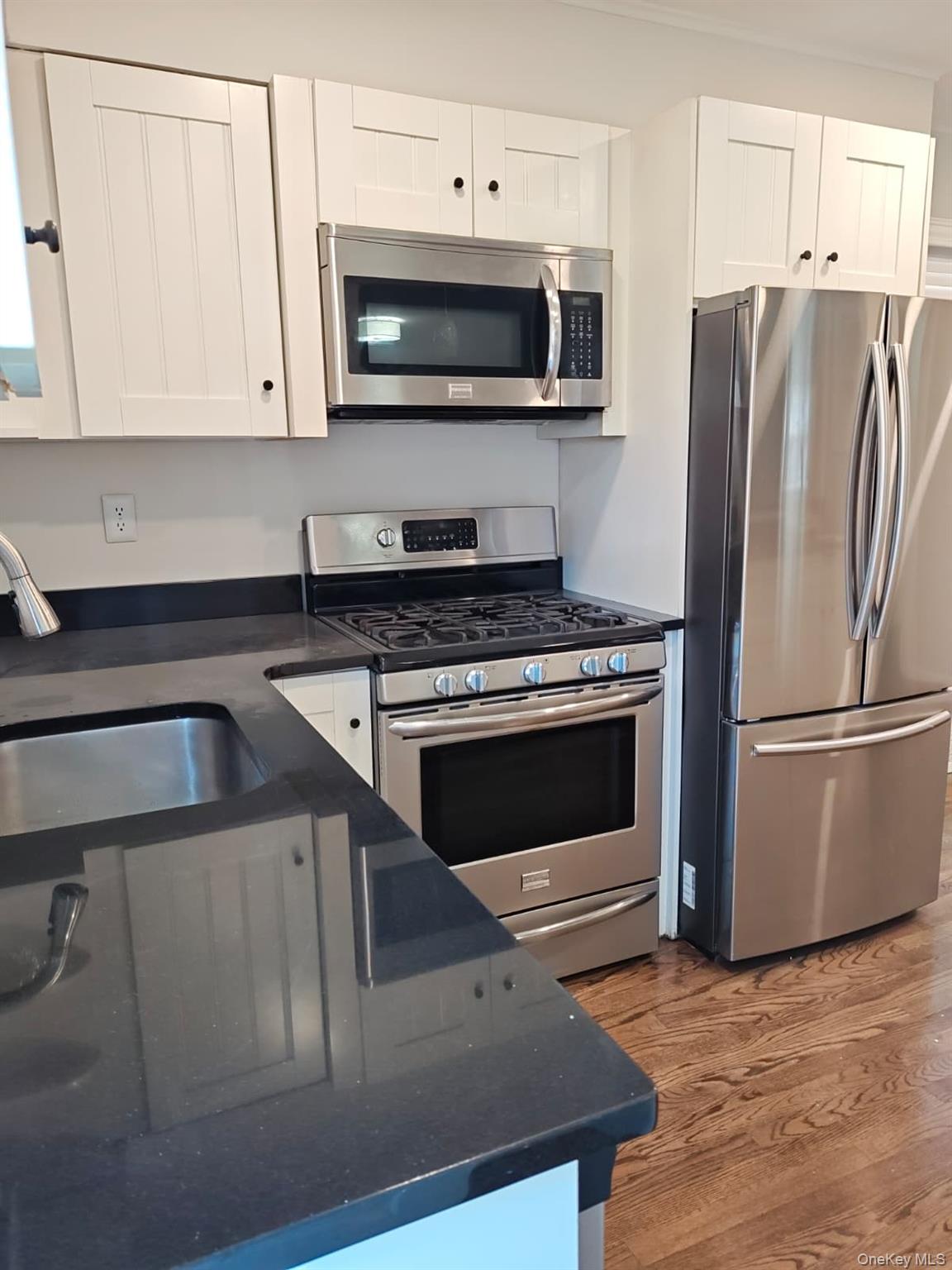 2354 North Wading River Road Wading River, NY 11792 - Photo 5 of 20 Kitchen featuring stainless steel appliances, white cabinets, light wood-type flooring, and dark stone countertops