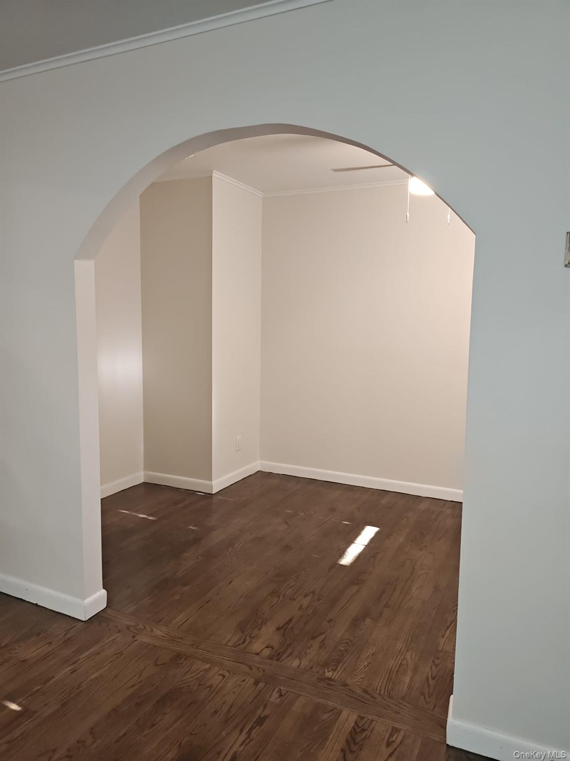 2354 North Wading River Road Wading River, NY 11792 - Photo 6 of 28 Empty room featuring arched walkways, ornamental molding, dark wood-type flooring, and ceiling fan