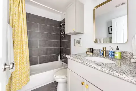 a bathroom with a granite countertop sink a toilet a mirror and bathtub