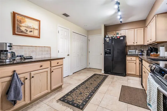 a kitchen with stainless steel appliances granite countertop a stove top oven a sink dishwasher and a refrigerator with wooden cabinets