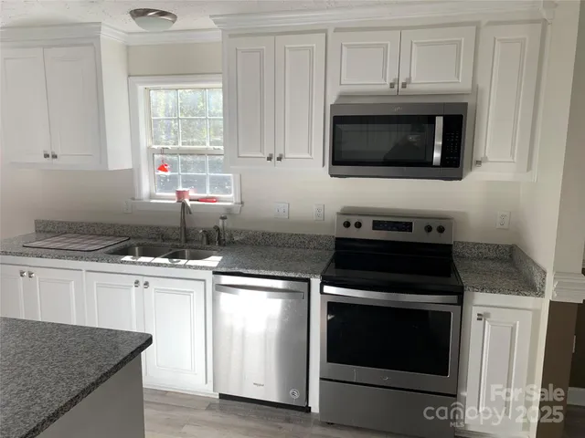 a kitchen with granite countertop white cabinets stainless steel appliances and sink