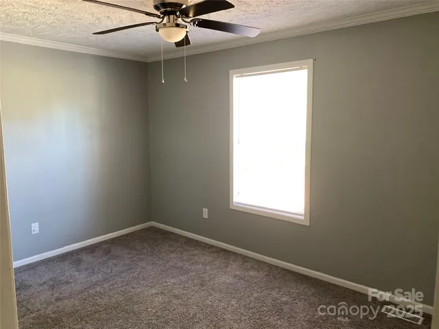 an empty room with a window and a fan