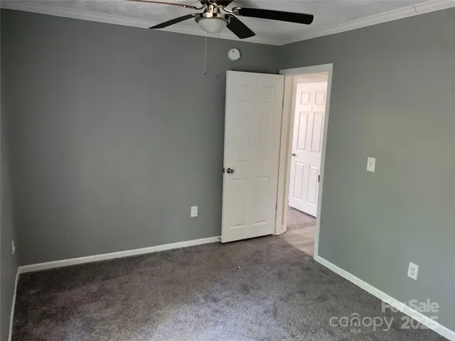 an empty room with a ceiling fan and carpet
