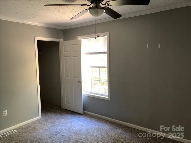 an empty room with a window and a ceiling fan