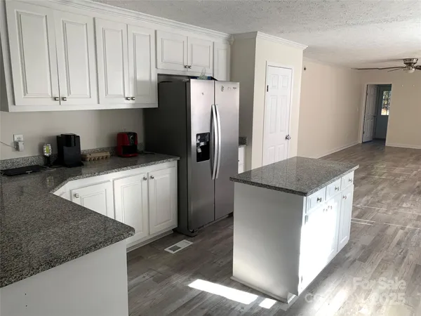 a kitchen with stainless steel appliances granite countertop a refrigerator a sink and white cabinets