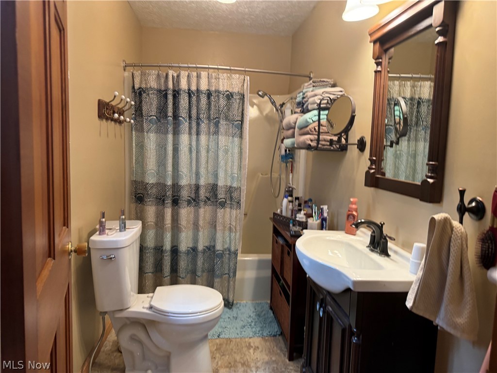 942 Webster Road Jefferson, OH 44047 - Photo 25 of 50 Full bathroom featuring tile patterned flooring, a textured ceiling, toilet, vanity, and shower / tub combo