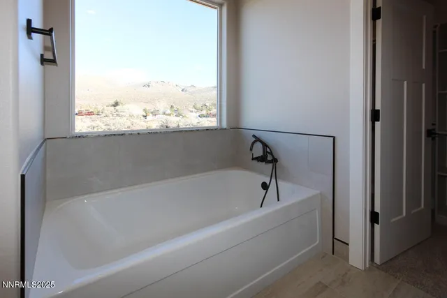 a white bath tub sitting in a bathroom next to a window