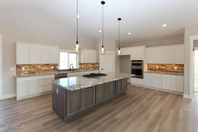 a large kitchen with granite countertop a stove a sink a center island and stainless steel appliances