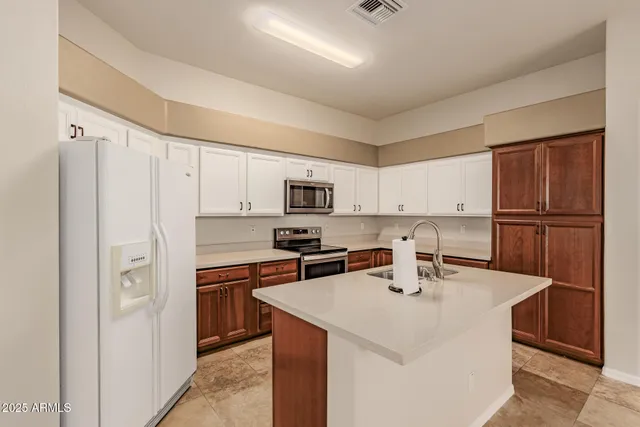 a kitchen with stainless steel appliances granite countertop a refrigerator a sink dishwasher a stove and white countertops with wooden floor