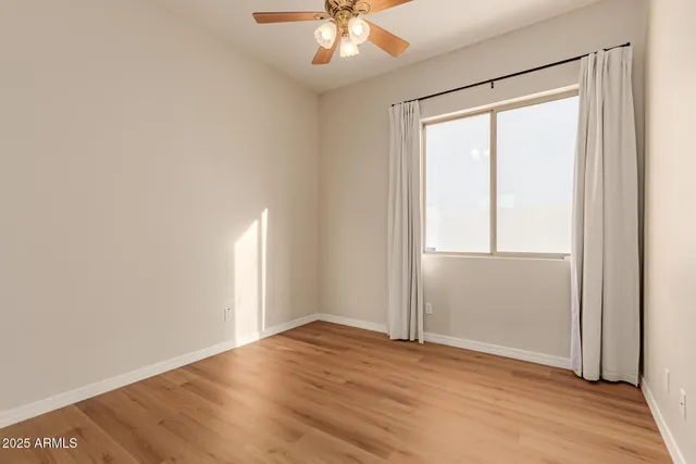 an empty room with wooden floor fan and windows