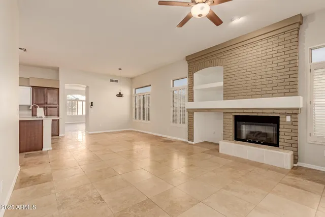 a view of an empty room with a fireplace and a ceiling fan