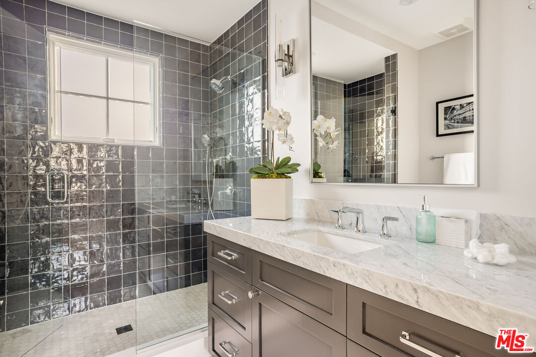 628 10th Street Santa Monica, CA 90402 - Photo 41 of 48 a bathroom with a granite countertop sink a mirror a bathtub and shower