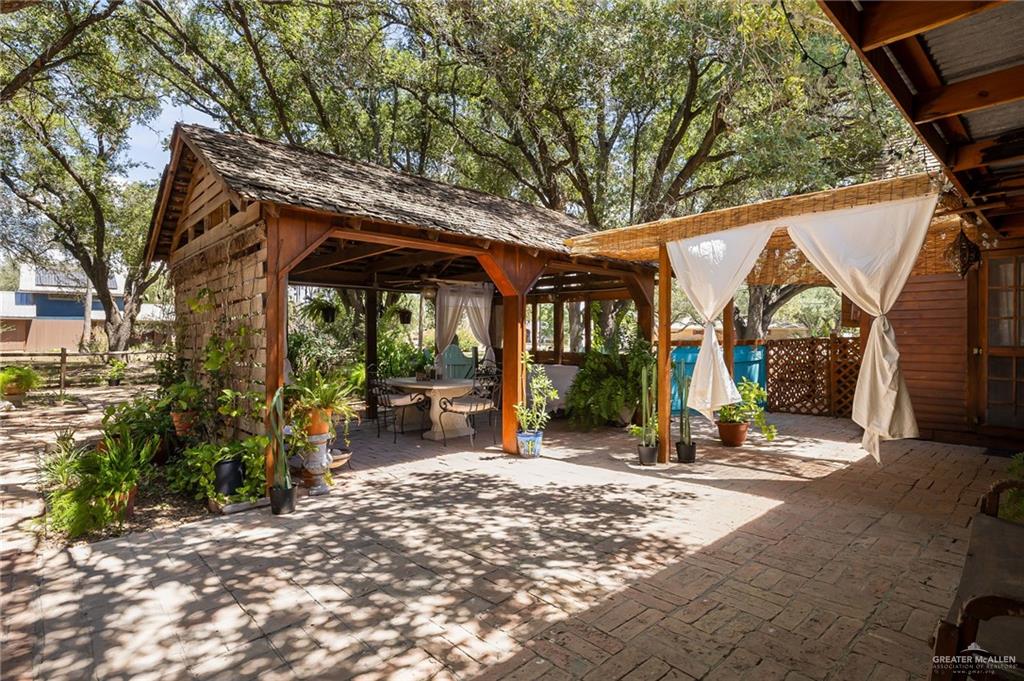 1803 North Bryan Road Mission, TX 78572 - Photo 20 of 30 Outdoor living space featuring a wood-shingled gazebo, a covered patio with draped fabric, and brick-style paving