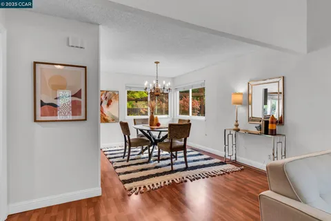 a dining room with wooden floor a glass table and chairs
