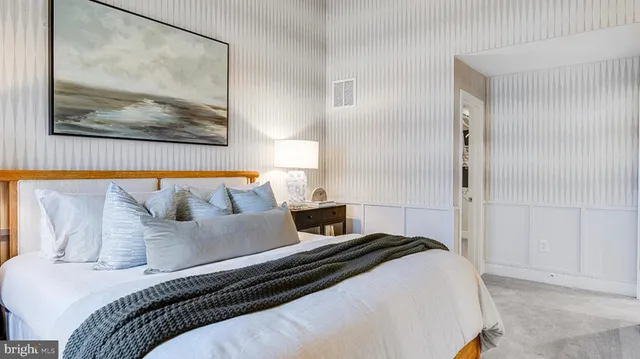 a bedroom with a large bed and a painting on the wall