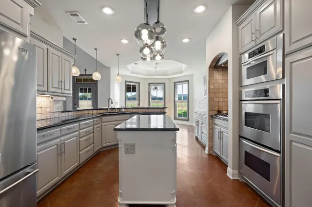 a kitchen with granite countertop white cabinets and stainless steel appliances