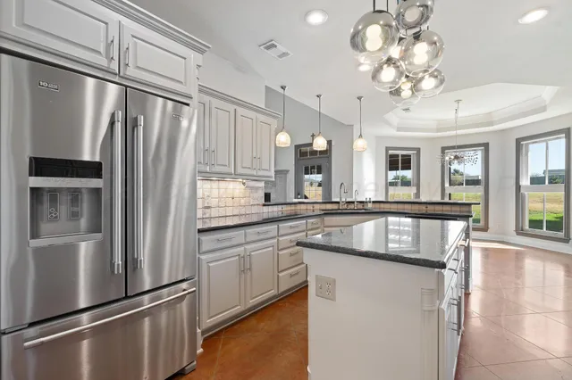 a kitchen with stainless steel appliances granite countertop a refrigerator a sink and a stove