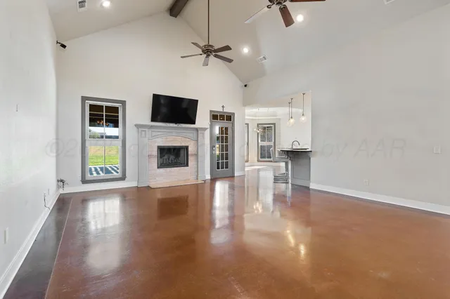 an empty room with windows fireplace and wooden floor