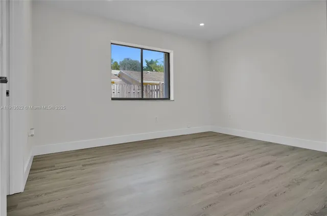 an empty room with wooden floor and window