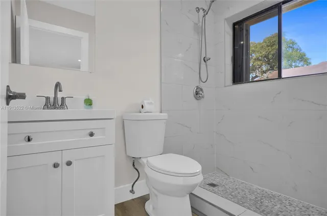 a bathroom with a granite countertop toilet sink and mirror