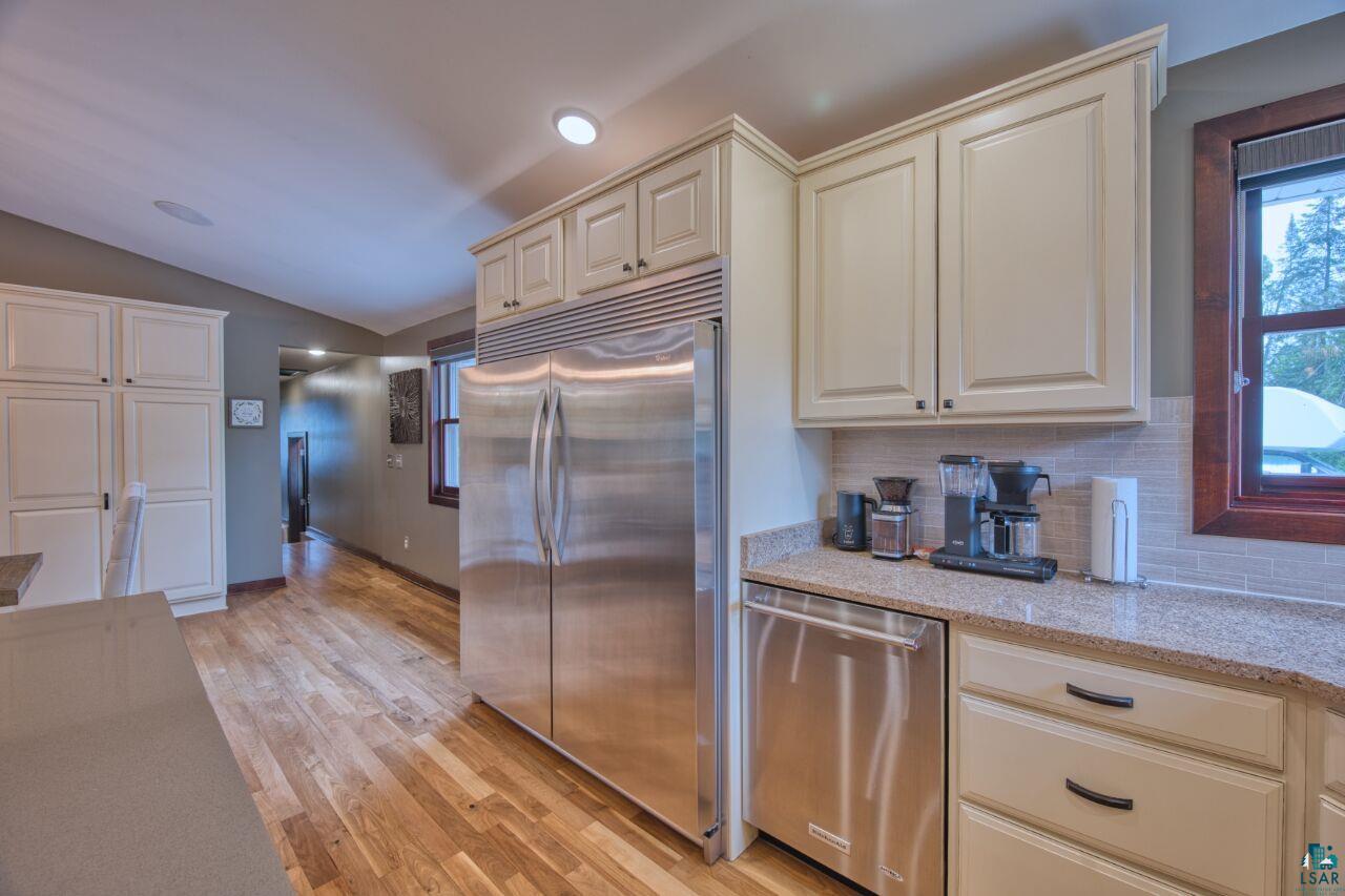 3557 Haverkamp Road Hibbing, MN 55746 - Photo 10 of 60 Kitchen with appliances with stainless steel finishes, vaulted ceiling, decorative backsplash, light wood-style floors, and light stone countertops