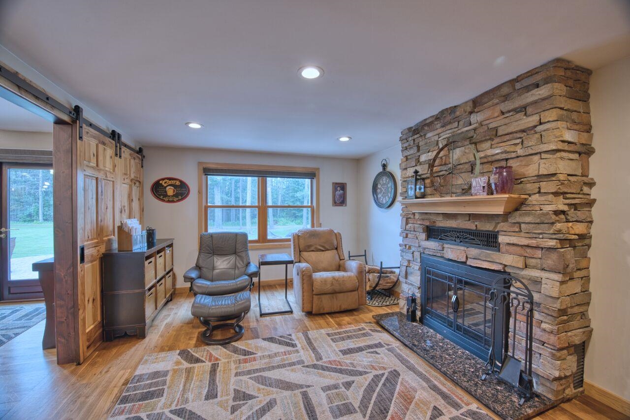 3557 Haverkamp Road Hibbing, MN 55746 - Photo 22 of 60 Living area with light wood-style flooring, a barn door, a stone fireplace, and recessed lighting