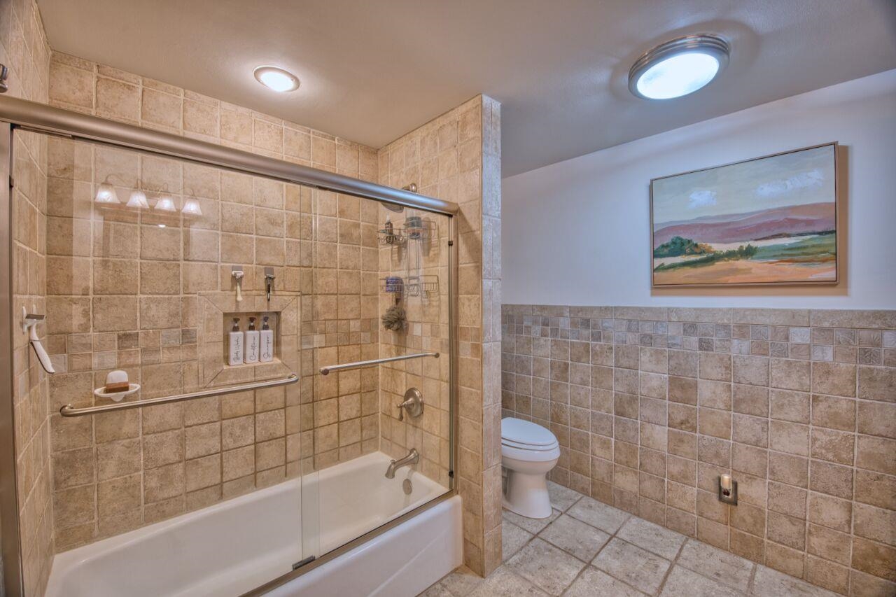 3557 Haverkamp Road Hibbing, MN 55746 - Photo 27 of 60 Full bath with tile walls, bath / shower combo with glass door, wainscoting, and tile patterned floors
