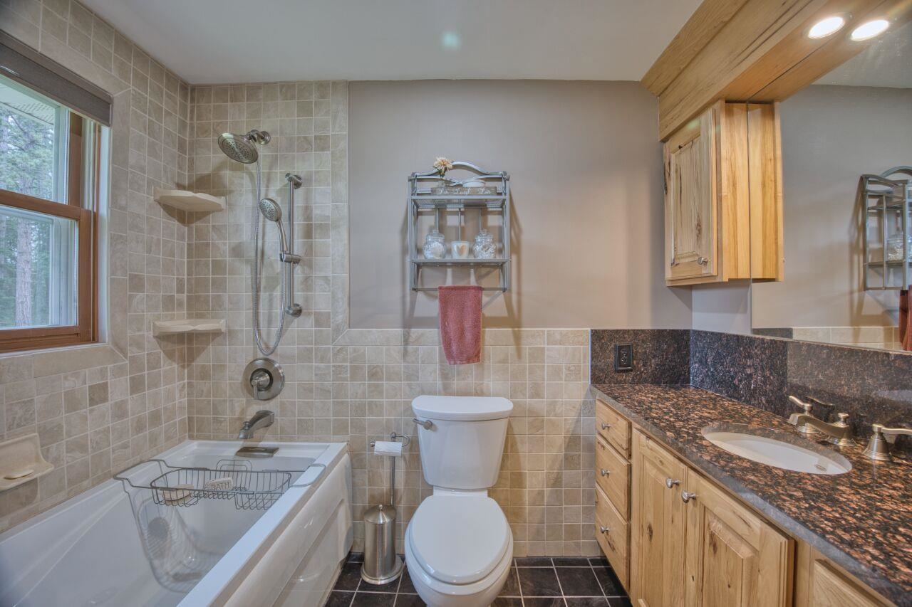 3557 Haverkamp Road Hibbing, MN 55746 - Photo 30 of 60 Bathroom with tile walls, vanity, tub / shower combination, tile patterned flooring, and a wainscoted wall