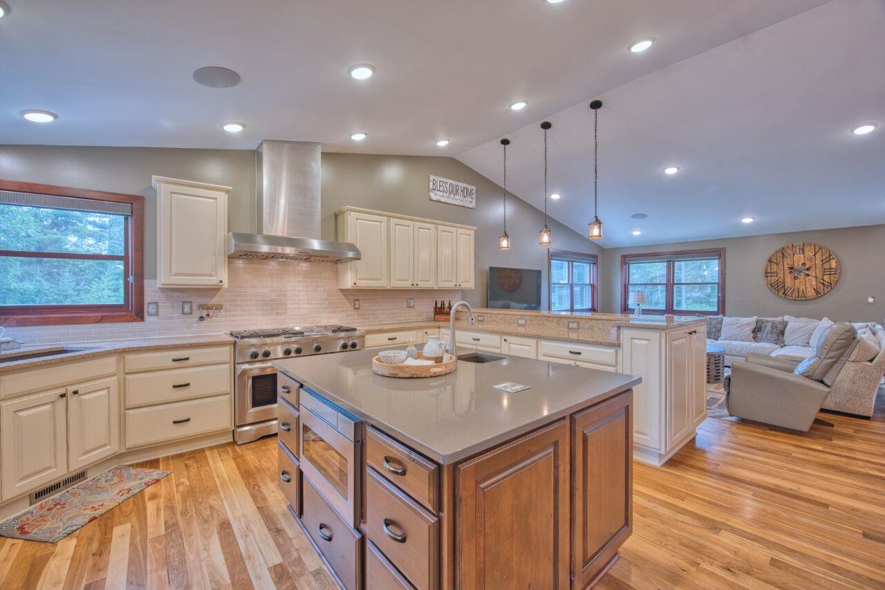 3557 Haverkamp Road Hibbing, MN 55746 - Photo 59 of 60 Kitchen with wall chimney range hood, lofted ceiling, stainless steel appliances, open floor plan, and light wood-style floors