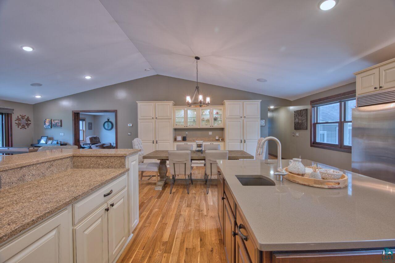 3557 Haverkamp Road Hibbing, MN 55746 - Photo 8 of 60 Kitchen featuring light wood-style flooring, lofted ceiling, a chandelier, built in refrigerator, and light stone counters