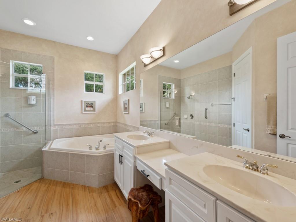 6840 Bent Grass Drive Naples, FL 34113 - Photo 11 of 21 a bathroom with a sink a large mirror and a bathtub
